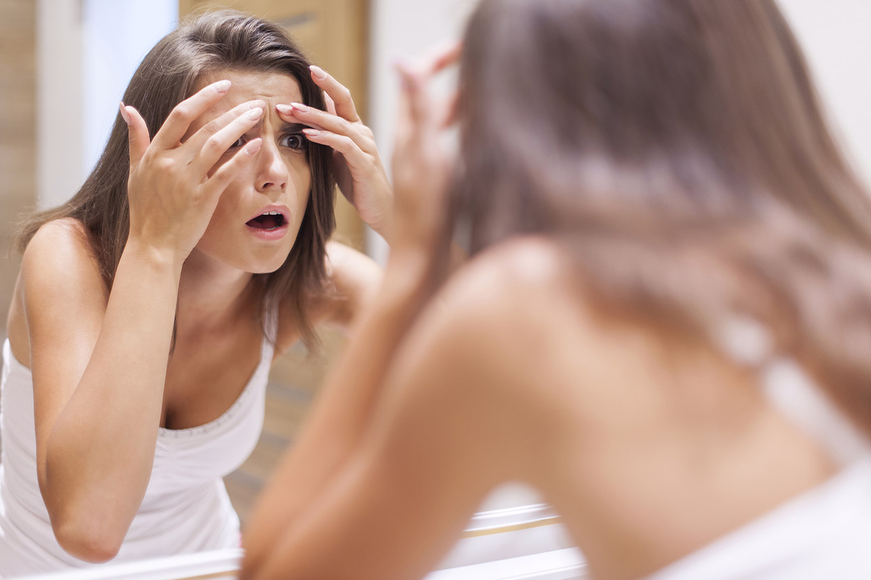 Woman looking at pimple in the mirror
