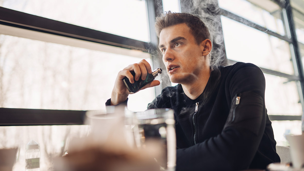 Young man vaping in closed public place